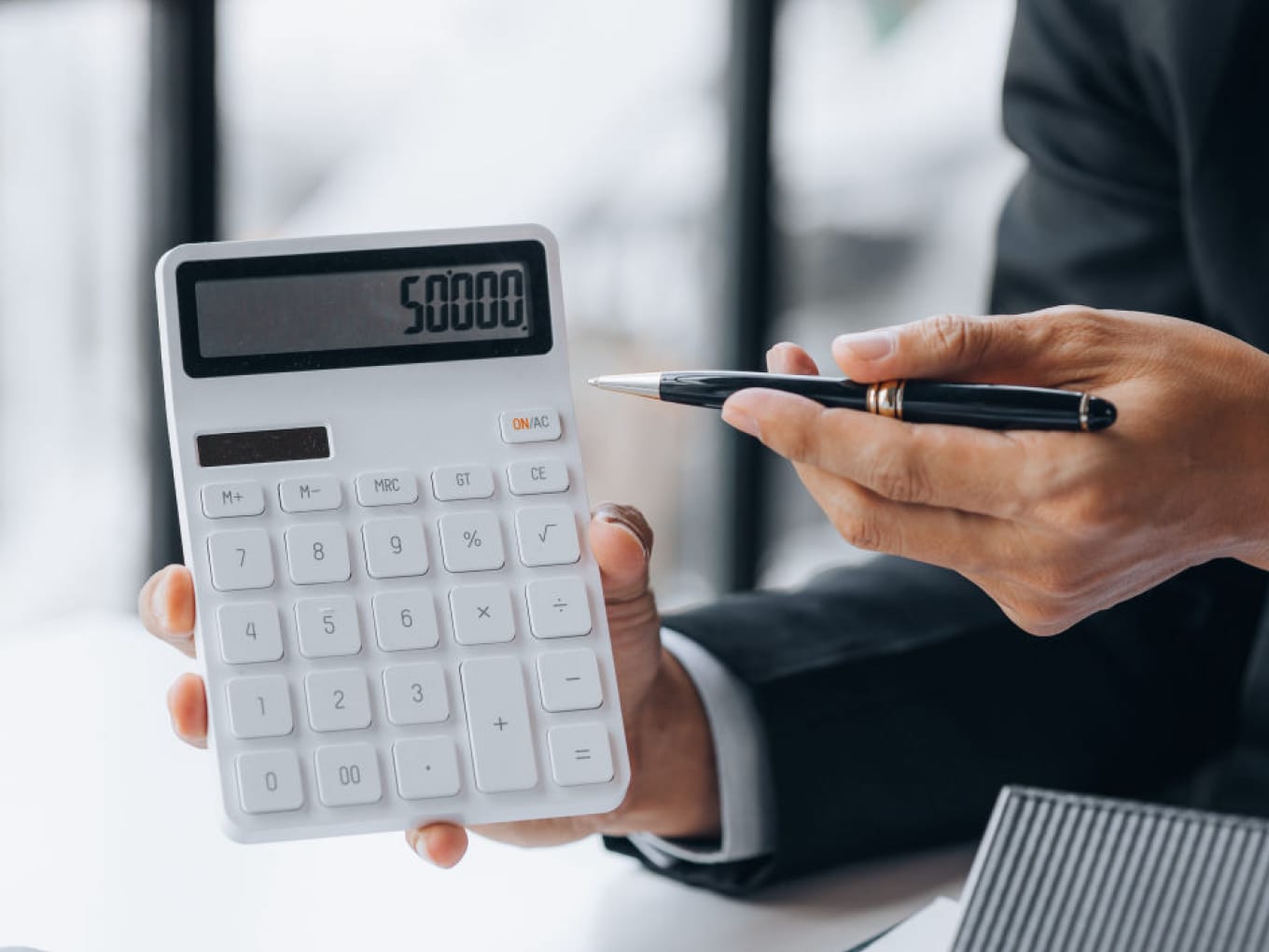 Man pointing to a calculator which reads 50000